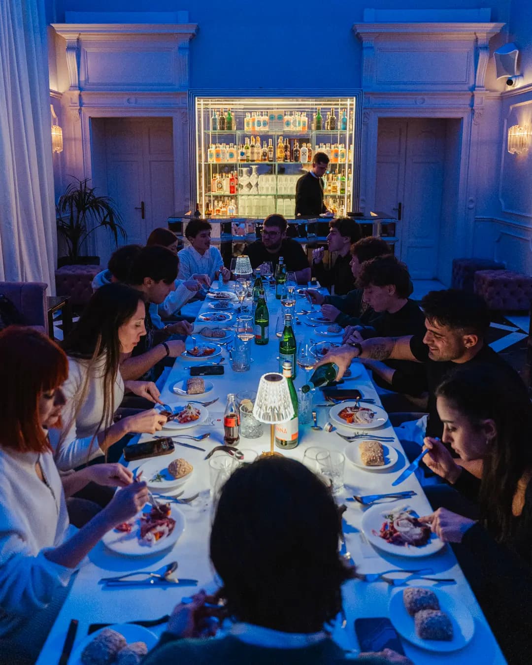 Lounge privata con atmosfera scura e accenti magenta per private dinner Élite